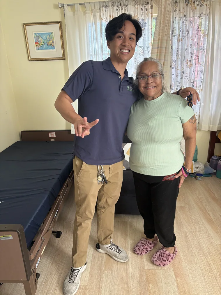 Caregiver and resident smiling together in comfortable bedroom setting