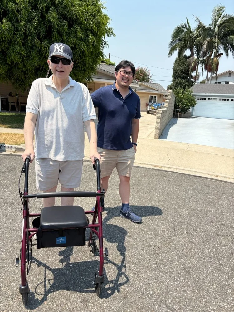 Caregiver assisting resident with mobility walker during outdoor walk