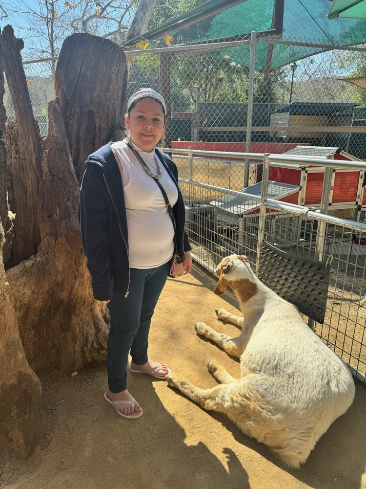 Resident enjoying time with a goat during an outdoor animal therapy activity