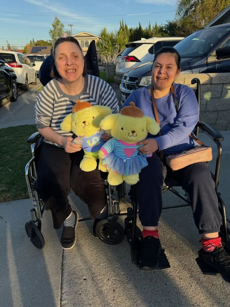 Two smiling residents in wheelchairs enjoying time together outdoors