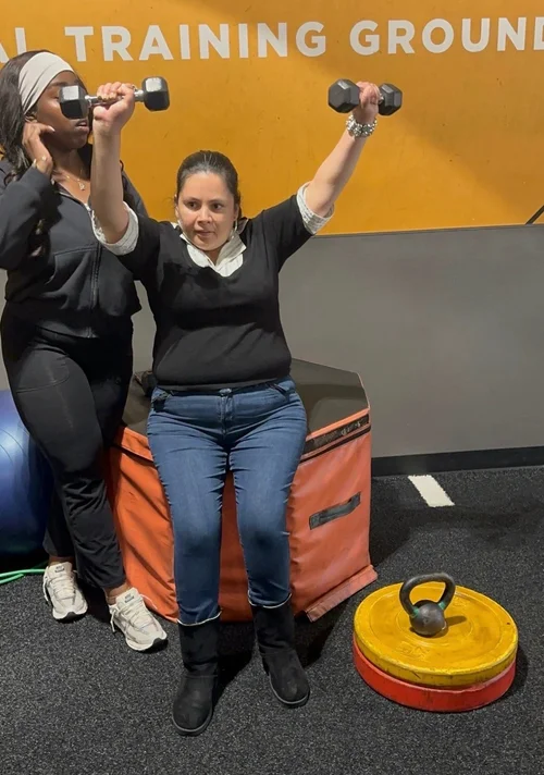 Caregiver assisting resident with upper body strength training exercise
