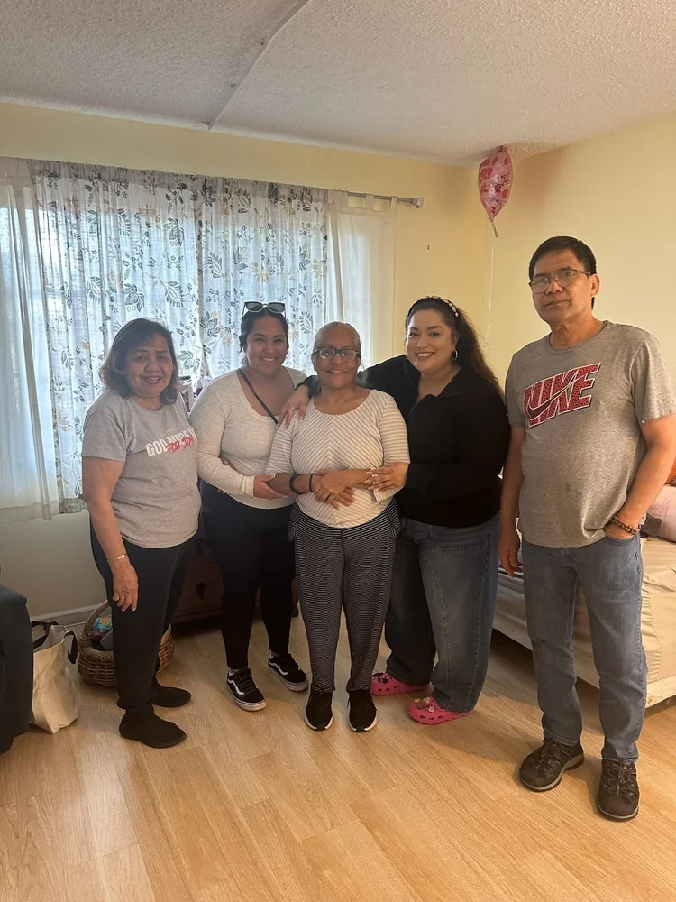 Five care staff members posing together in a comfortable residential living room