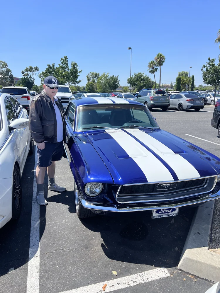 Resident enjoying a community outing with a classic Ford Mustang on a sunny day